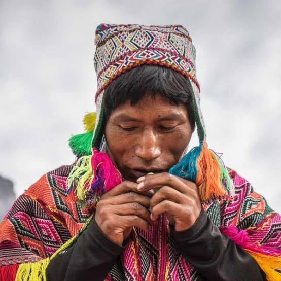 Quechua elder in prayer with sacred flute
